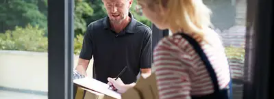 Someone at their home frond door signing a package sending form