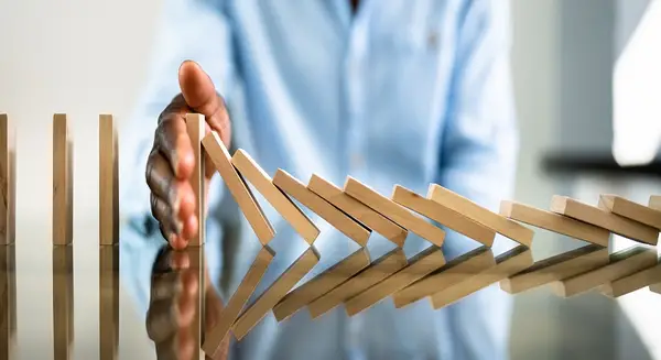 a hand preventing additional dominos from being knocked over